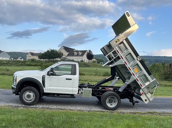 Municipal work truck with aluminum dump body raised, showing the Buyers center-discharge spreader insert