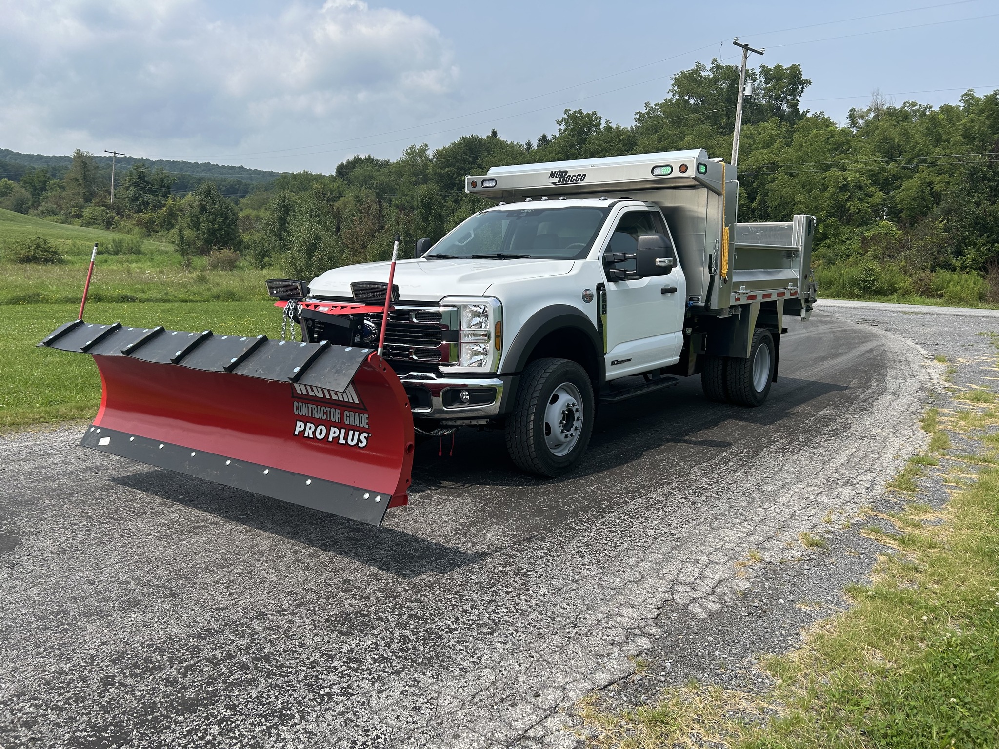 White single-axle municipal dump truck with a red Western 9-foot Pro Plus snow plow mounted on the front and a Morocco Welding aluminum dump body.
