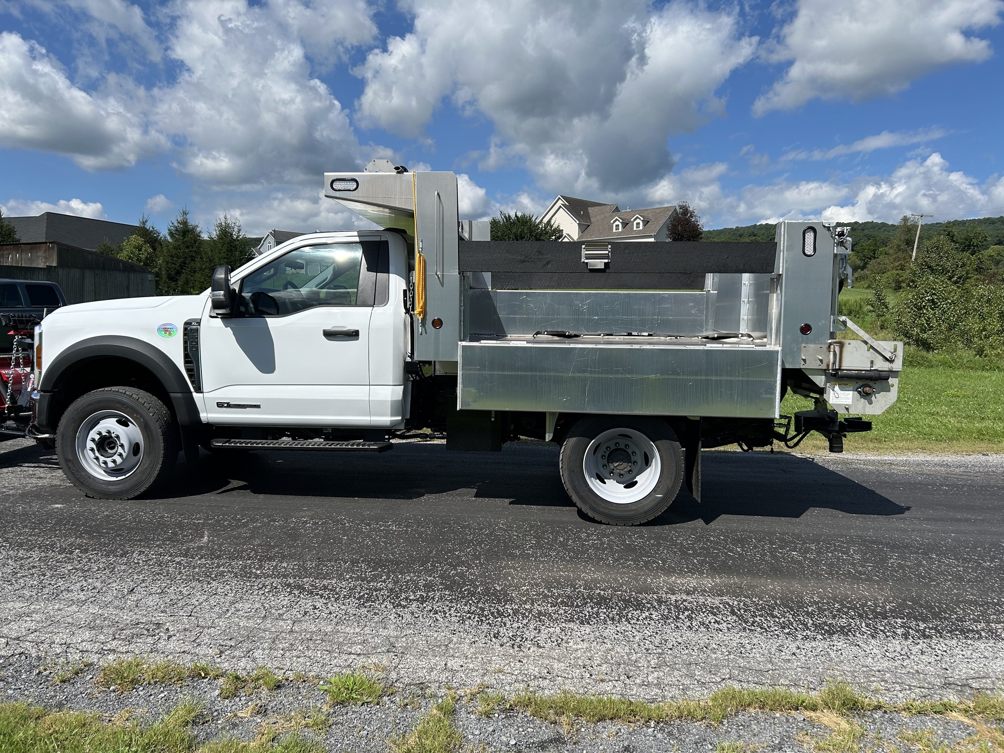 Side profile of a white municipal work truck fitted with a Morocco Welding aluminum dump body with fold-down sides.